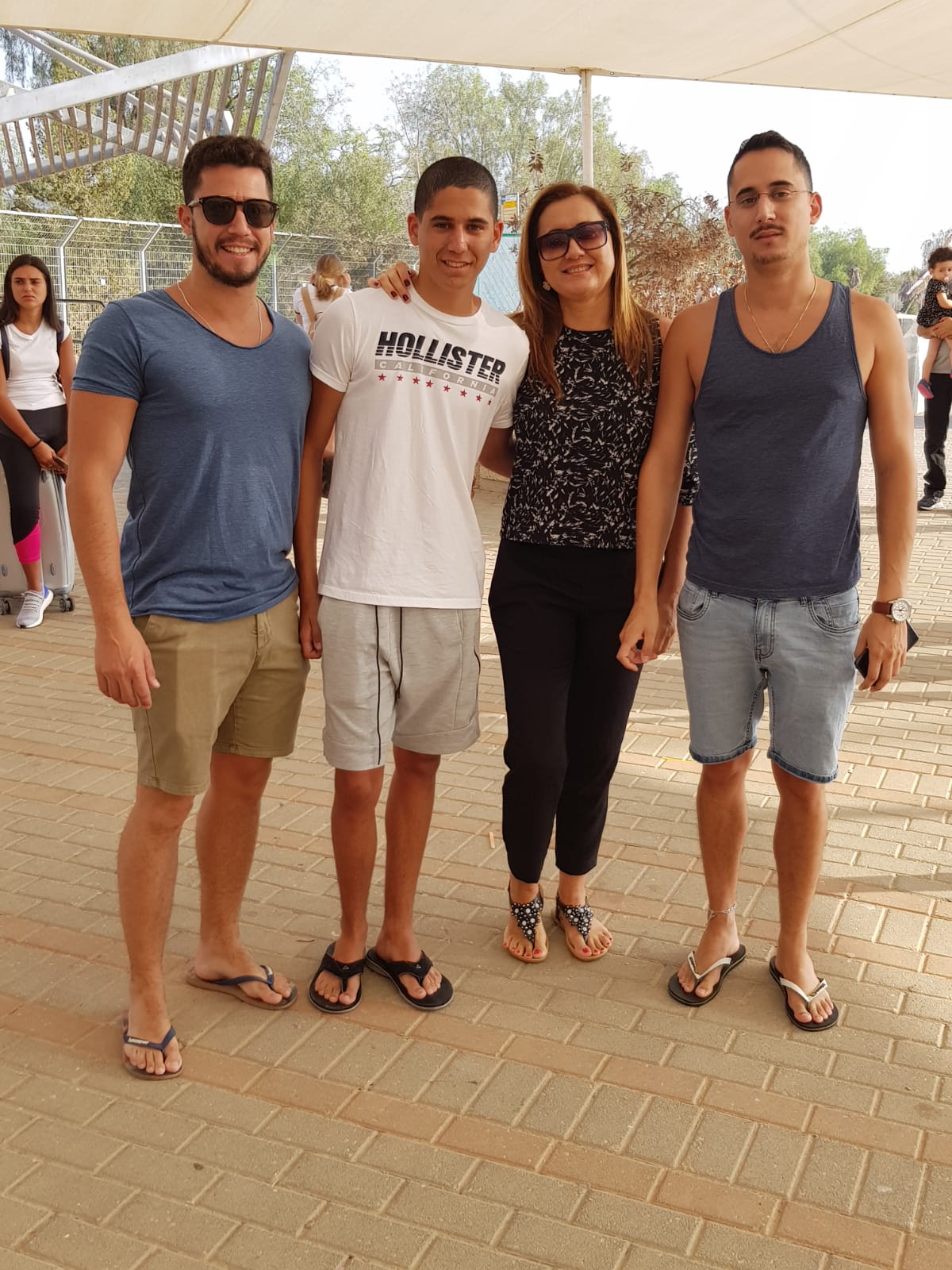 תמיר עומד בחוץ עם שני צעירים ואישה, כולם מחובקים ומחייכים.