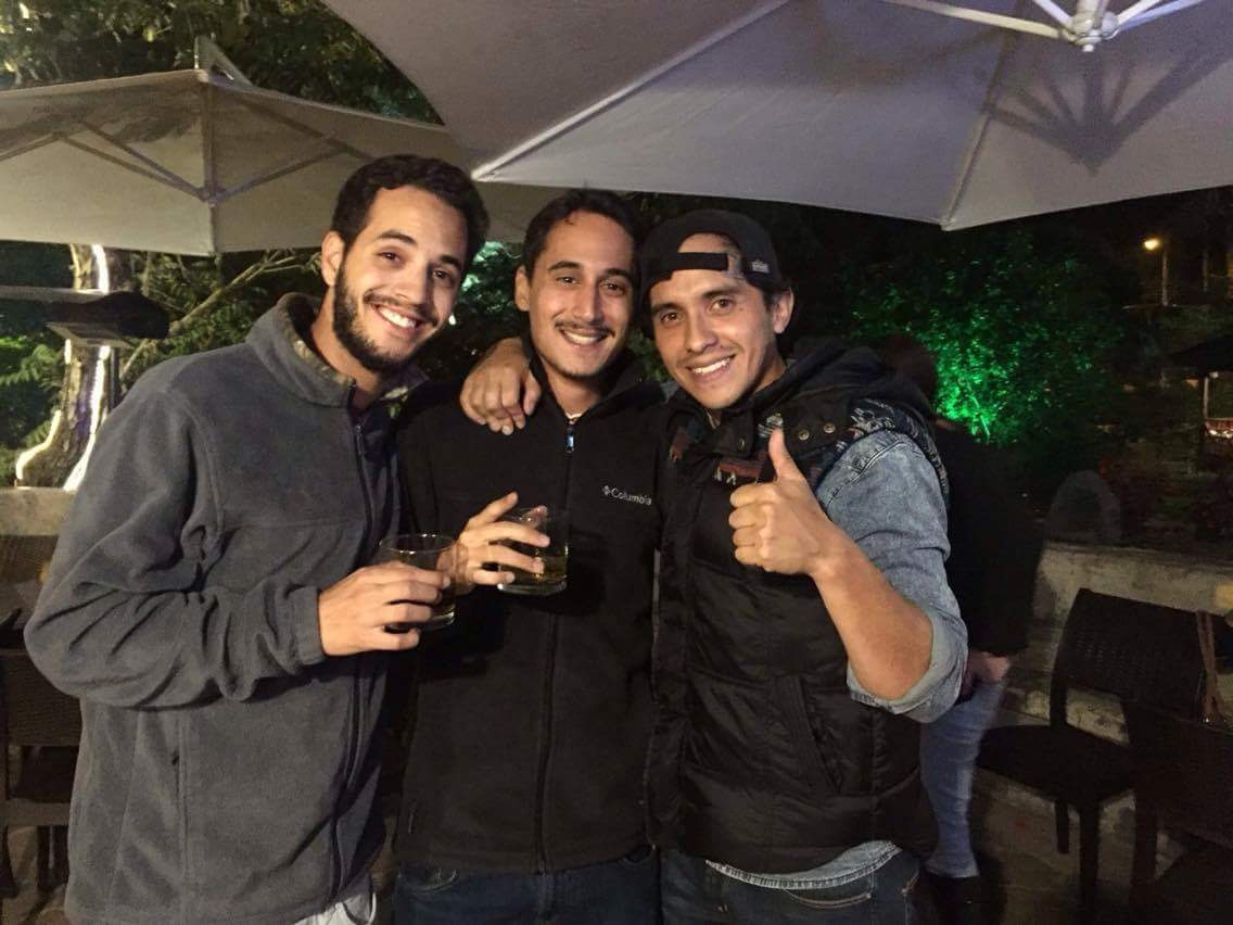 תמיר ושני חברים בערב בחוץ, מחייכים ומרימים כוסות.