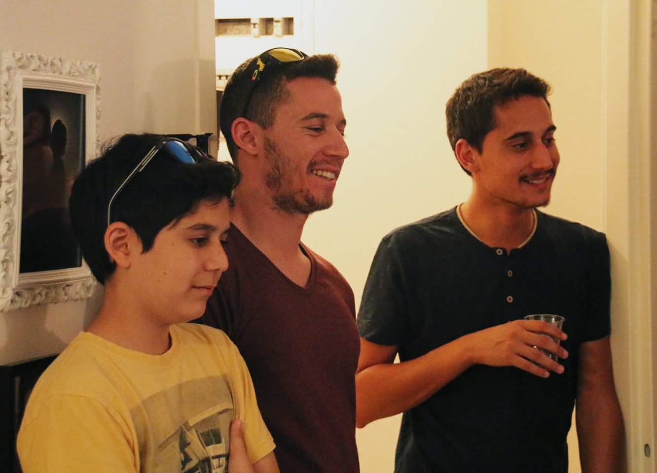 תמיר, צעיר נוסף ונער בחולצה צהובה עומדים יחד ומביטים הצידה בחיוך.